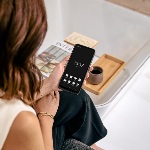 Punkt. MC02 privacy phone held by a woman next to a living room table.