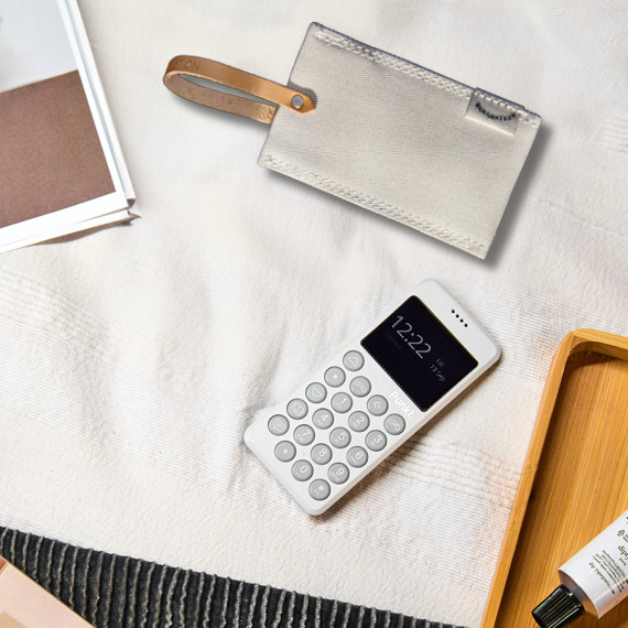 Punkt. MP02 light grey phone next to the grey QWSTION case on an off-white tablecloth.