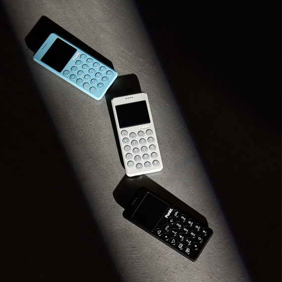 Three MP02 phones (light blue, light grey, black) on a dark floor, with shadows.